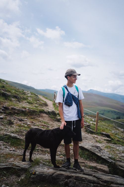 Teenager hiking a mountain trail with his dog trotting alongside