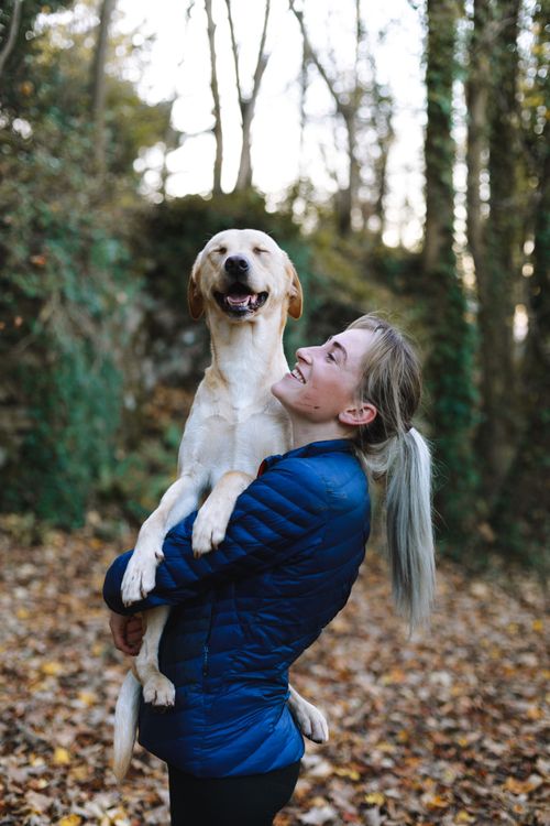 woman carrying her tan dog in her arms