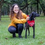woman smiling with an adoptable black dog in a park