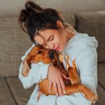 owner hugging her dog on the couch at home