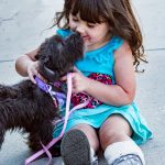 dog sitting beside a little girl on the floor