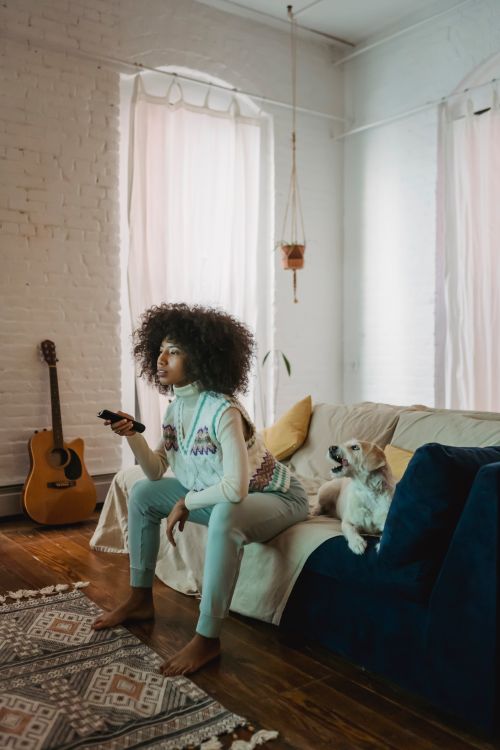 woman sitting on a couch with her dog while watching television