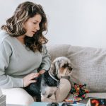 dog watching television next to its owner on the couch