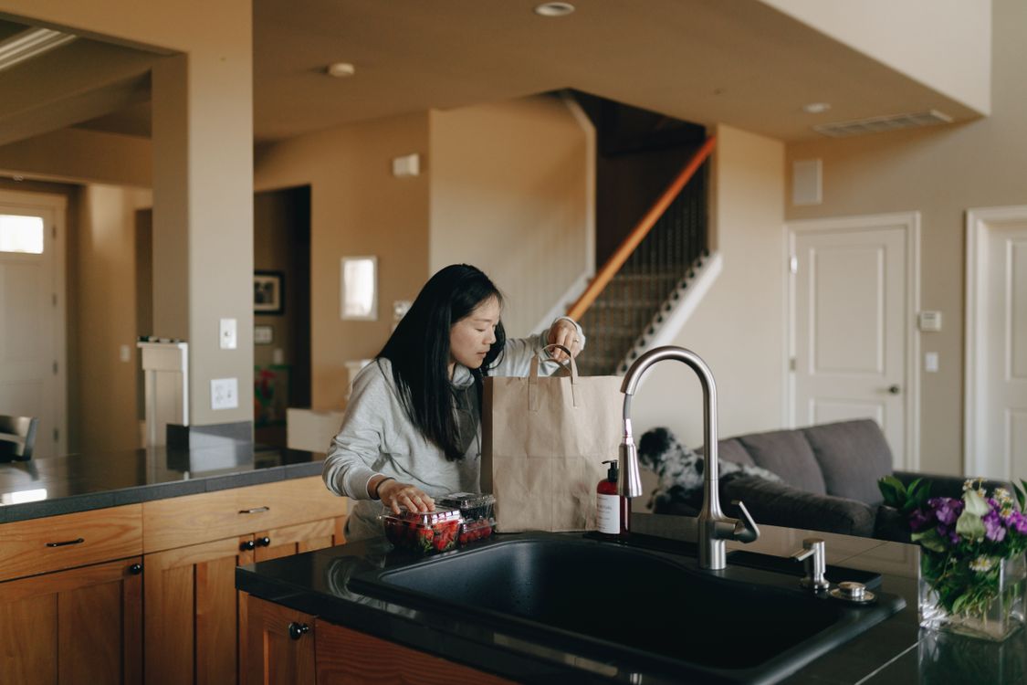 Dog standing beside a paper grocery bag while groceries are unpacked on the kitchen counter