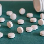 white pills spilled from a bottle onto a table
