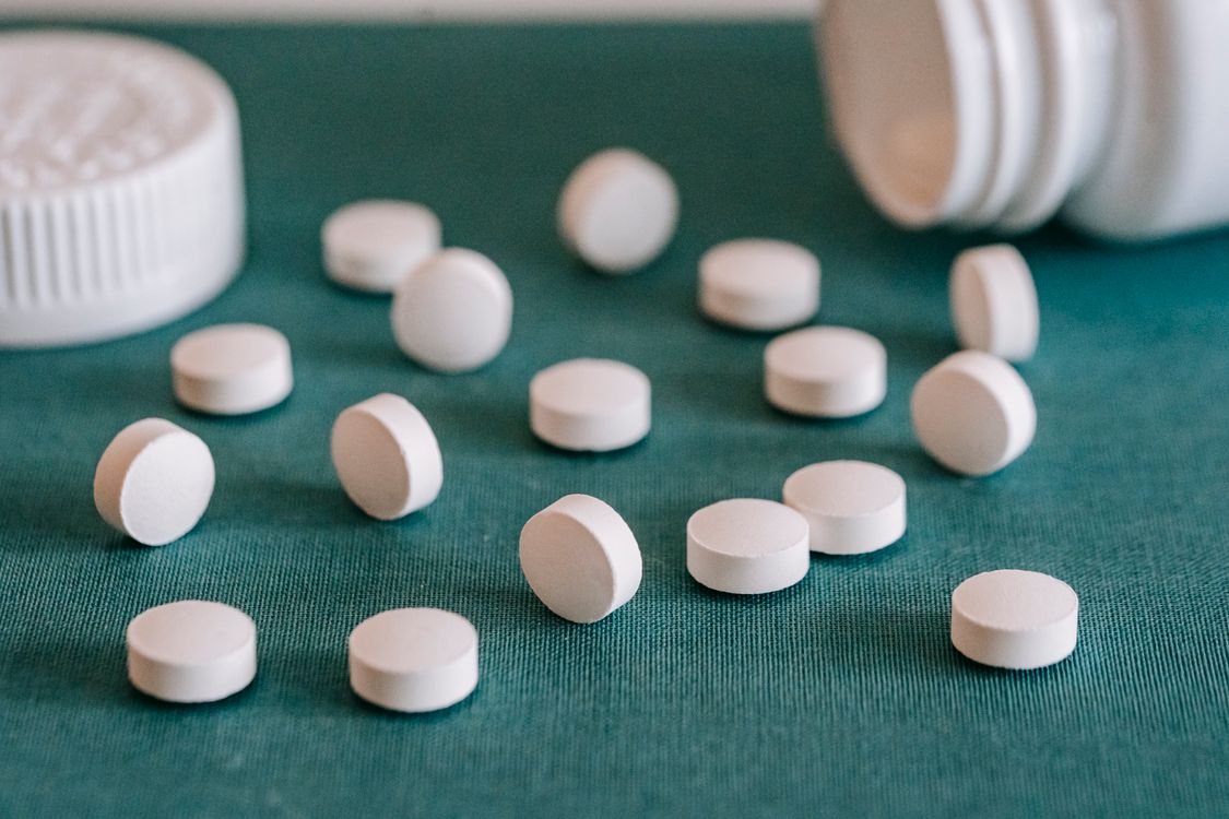 white pills spilled from a bottle onto a table