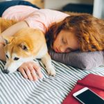 A woman sleeping in bed beside her dog