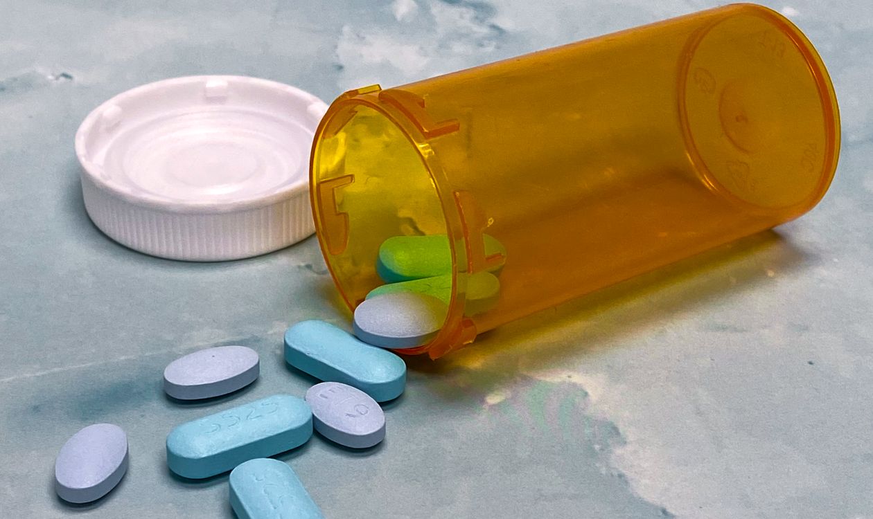 Prescription pills beside a medicine vial on a table