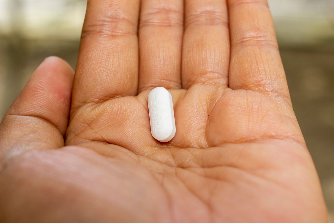 hand holding a single white oval tablet