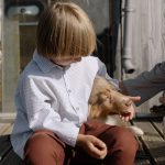 two children playing with a golden retriever in a garden